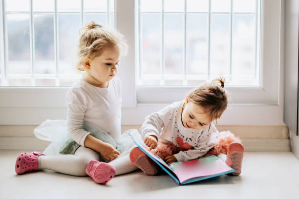 istock Sisters reading a book together in a window seat 1151486484