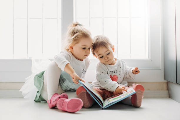 istock Sisters reading a book together in a window seat 1151486675