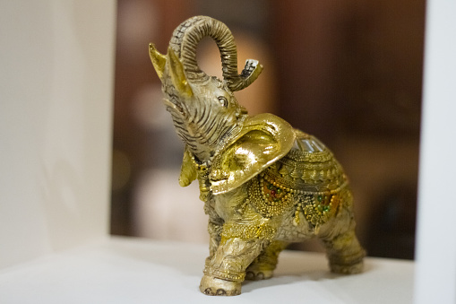 Bronze figure of an elephant with a raised trunk in the interior of a yoga studio, selective focus.