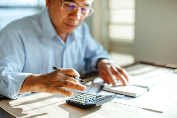 istock Senior Taiwanese man using calculator at home 1151494059