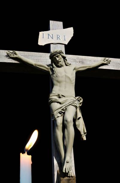 candela accesa che brilla davanti alla statua di cemento di gesù - jesus christ cross old statue foto e immagini stock