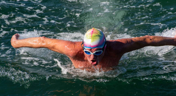 istock Older man swimming butterfly stroke in the ocean. 1151509959