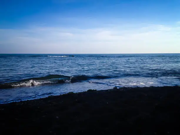 Black Sand And Calm Beach Water Horizon View In The Morning At Umeanyar Village, North Bali, Indonesia