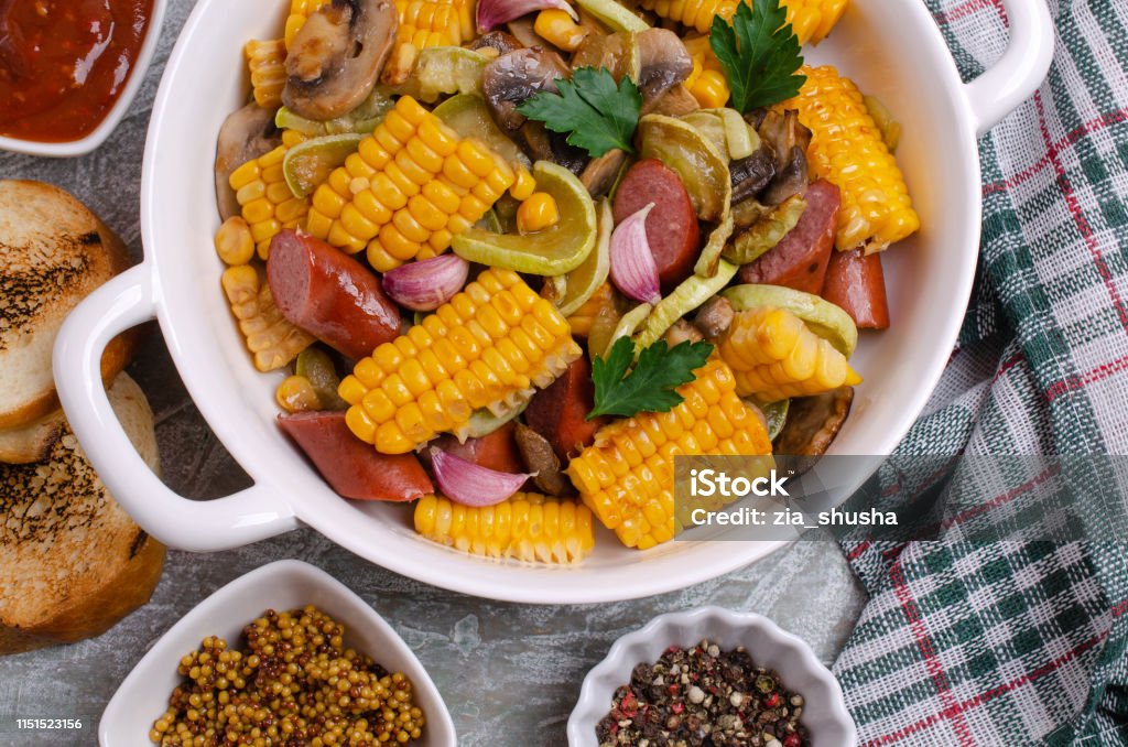 Slices of fried vegetables with sausages Slices of fried vegetables with sausages and spices on a slate background. Selective focus. Agaricus Stock Photo