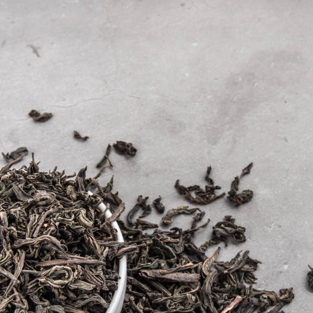 istock Dried tea is poured into a white ceramic cup on a gray textured background. 1151527230