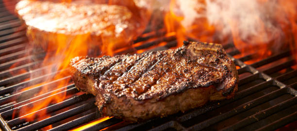 rib-eye steaks cooking on flaming grill panorama rib-eye steaks cooking on flaming grill panorama close up steak stock pictures, royalty-free photos & images