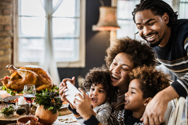 Happy African American family taking a selfie during Thanksgiving lunch. Happy black family having fun while taking a selfie on Thanksgiving lunch at dining table. turkey meat photos stock pictures, royalty-free photos & images