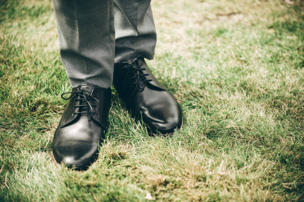 istock Low Section Of Man Wearing Leather Shoes While Standing On Grass 1151549779