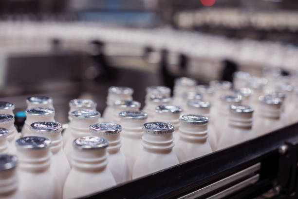 bottiglie di latte fresco che si muovono sul nastro trasportatore in un caseificio in africa - milk bottle milk plastic bottle foto e immagini stock