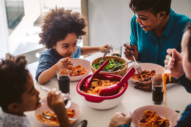 Family Lunch At Home Cute mixed race family having lunch at home. kids eating noodles stock pictures, royalty-free photos & images