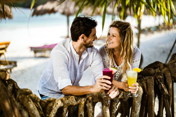 istock Happy couple talking while enjoying in drinks on the beach. 1151551785