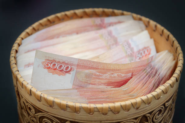 A lot of banknotes worth five thousand rubles are in a round wooden wicker box.