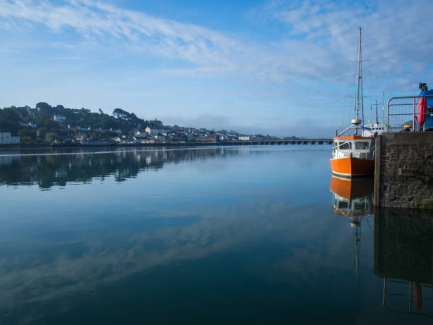 istock Small orange boat reflecting in the calm waters at Bideford Quayside in Devon 1151561315