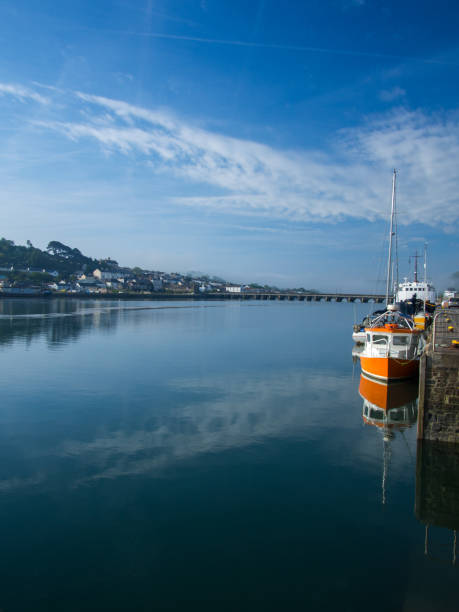 istock Small orange boat reflecting in the calm waters at Bideford Quayside in Devon 1151561319