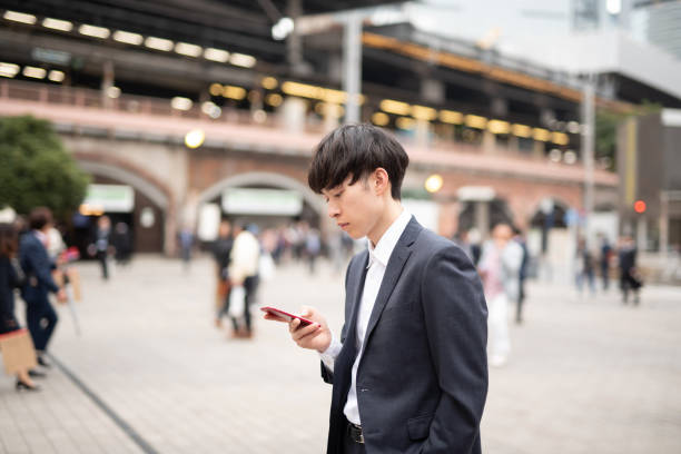 istock Young businessman standing among crowd with smart phone in hand 1151566341