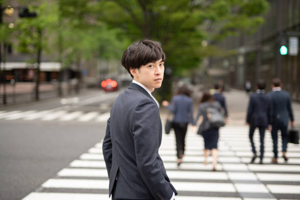 通りを振り返っている若いビジネスマン - オフィス街　日本 ストックフォトと画像