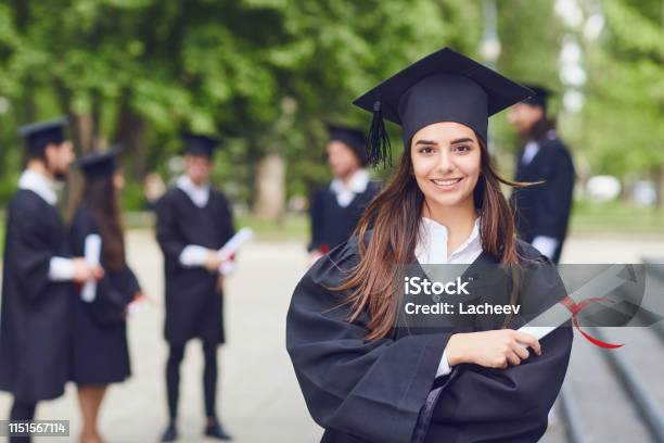 A Young Female Graduate Against The Background Of University Graduates Stock Photo - Download Image Now