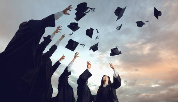 istock A group of graduates throws hats up into the sky. 1151567160