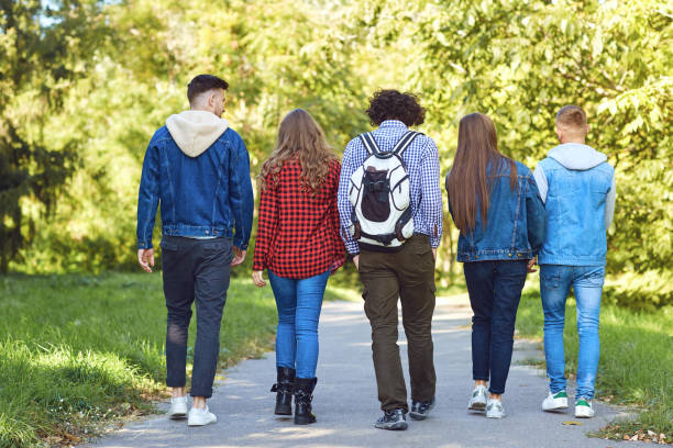 istock Back view. Friends walk in the park. 1151568290