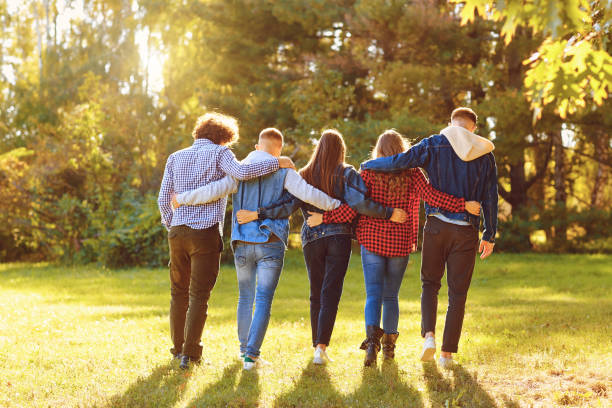 istock Embracing friends walking together in park 1151568307