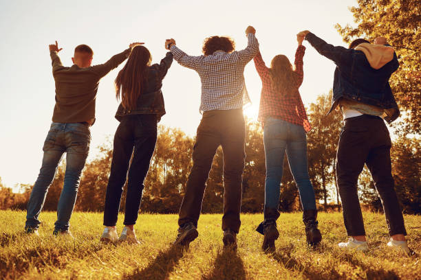 istock People standing with arms raised on meadow 1151568314
