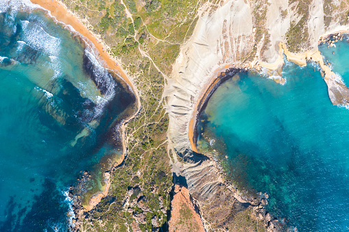 Aerial view from height of the isthmus of the peninsula coastlinescenic sliffs near the mediterranean turquoise water sea. Gnejna and Ghajn Tuffieha bay on Malta island