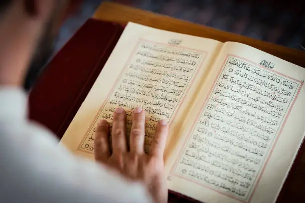 Muslim man reading Koran in mosque