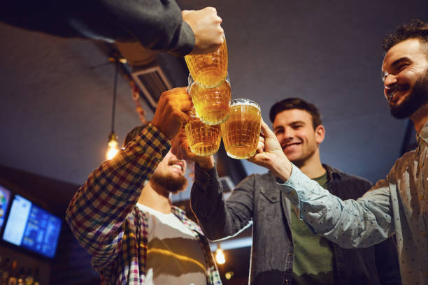 istock Young people clink glasses with beer in a bar. 1151574827