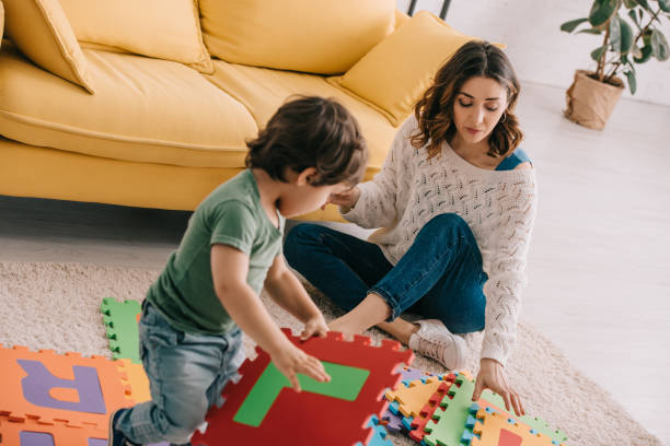istock Mother and son playing with alphabet puzzle mat on carpet 1151575795