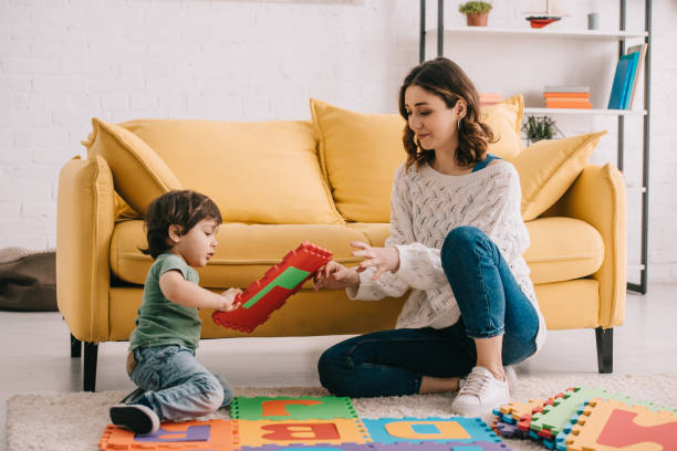 istock Mother and son playing with alphabet puzzle mat on carpet 1151575818