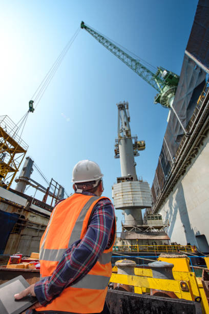 Loading Master stevedore or foreman, engineering, loading master talks to crane driver by walkie talkie for safety lifting the goods shipment, lifting by gantry crane, working at risk on the high level insurance gantry crane stock pictures, royalty-free photos & images