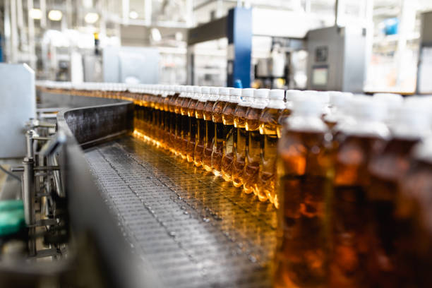 Production line for juice bottling Bottling factory - Apple juice bottling line for processing and bottling juice into bottles. Selective focus. carbonated juice stock pictures, royalty-free photos & images