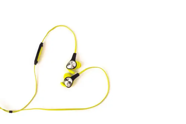 Wired earbud headphones in heart shape with copy-space isolated on white background