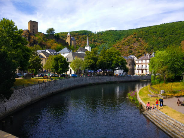 la rivière sure à travers esch-sur-sure avec le château d’esch-sur-sure en arrière-plan, au luxembourg. les gens jouant dans la rivière - esch sur sûre photos et images de collection