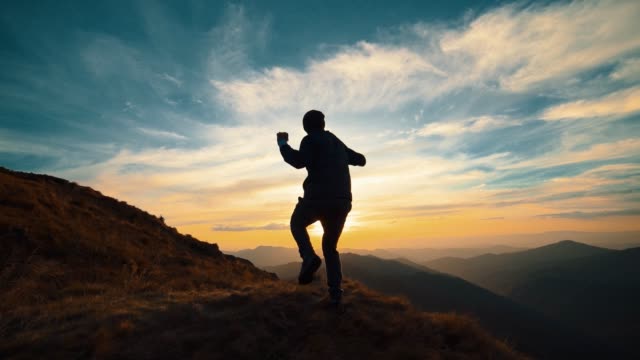 The man running on the mountain against the beautiful sunrise. slow motion