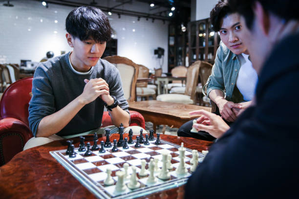 istock Young male friends playing chess in cafe 1151592936