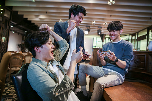 Young friends playing mobile game in cafe