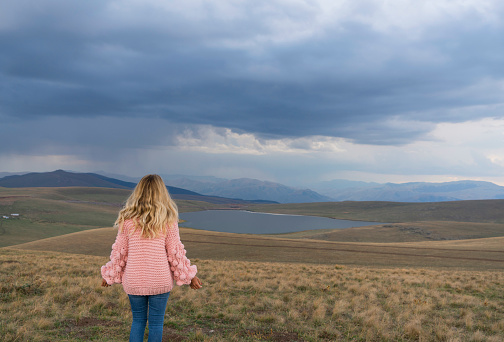 Woman sits on a hill and admires the beautiful view