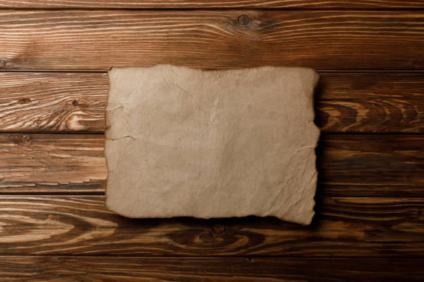 istock brown old parchment paper lying on wooden background 1151599182
