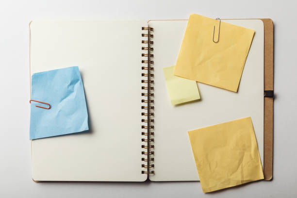 istock top view of opened notebook with blue and yellow sticky notes with paper clips on white background 1151599219