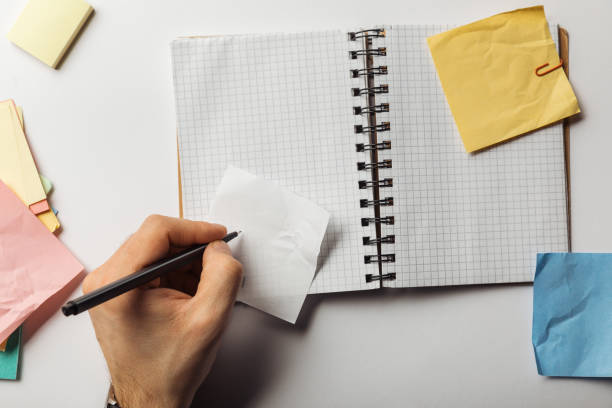 istock cropped view of man writing on sticky note near opened notebook 1151599249