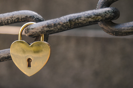 Love locks and hearts. Close-up of love lock with a red heart hanging on chain in on background of the sea. The key locks for lovers promise love. Concept image for valentine's day. Loyalty and love