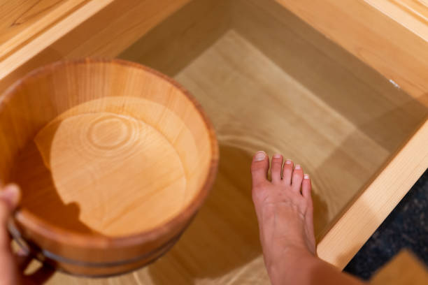 bañera de madera de ciprés tradicional cubo japonés en la bañera en el baño de hotel onsen interior en japón con pies entrando en el agua - 13584 fotografías e imágenes de stock