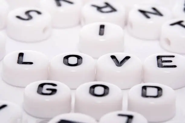 I love GOD word written with white buttons with black letters macro/close up side shot in a puzzle of alphabets