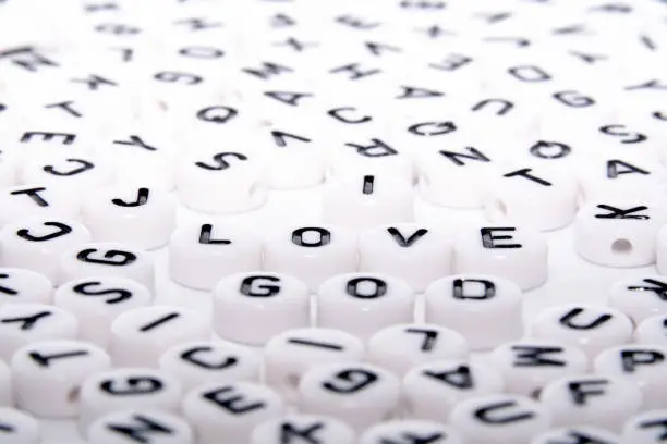 I love GOD word written with black letters on block/dice close up side shot in a puzzle of alphabets