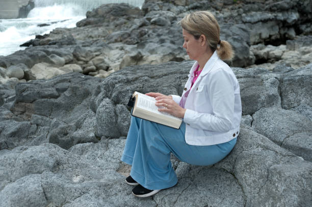 Young mixed race woman meditating on Bible in river. Beautiful place. Copy space. Horizontal shot.