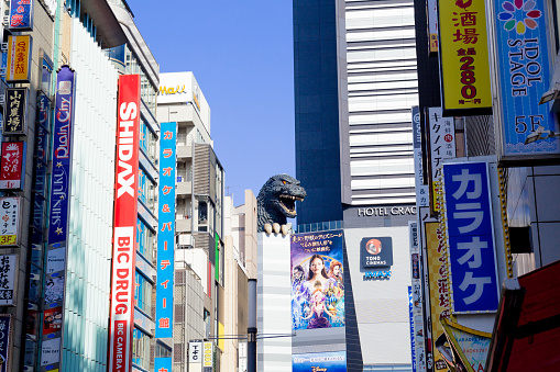 Tokyo, Japan - December 1, 2018: The life-sized replica of Godzilla overlooks the Kabukicho entertainment district from the eighth floor of Hotel Gracery