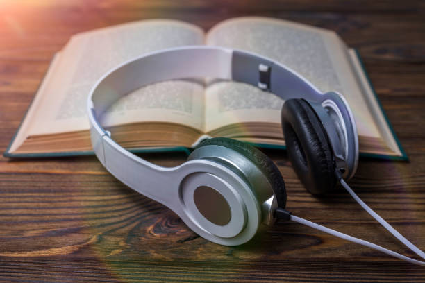 istock Headphones, open book on wooden background 1151608566