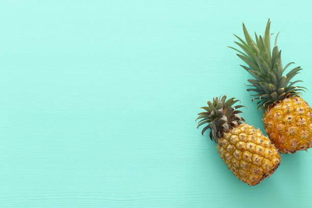 istock Ripe pineapple over mint wooden background. Beach and tropical theme. Top view 1151609616