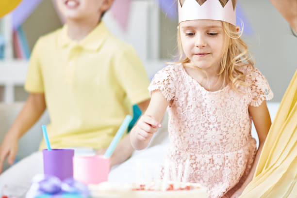 istock Cute girl counting candles on birthday cake 1151611255
